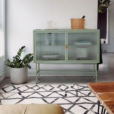 a living room with a green cabinet in the middle and a white rug on the floor