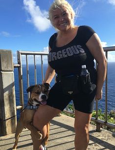 a woman standing next to a brown and white dog