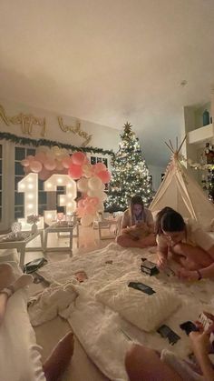 two children are sitting on the floor in front of a teepee tent with balloons