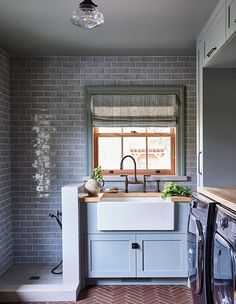 a washer and dryer in a small room with grey brick walls, flooring and cabinets