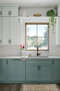 a kitchen with blue cabinets and white counter tops, along with a rug on the floor