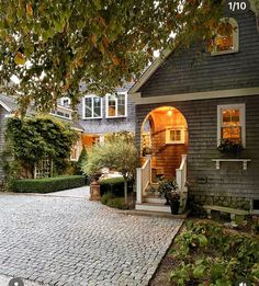 a house that is sitting on the side of a road with trees in front of it