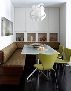 a dining room table with green chairs and a light fixture hanging over it's head