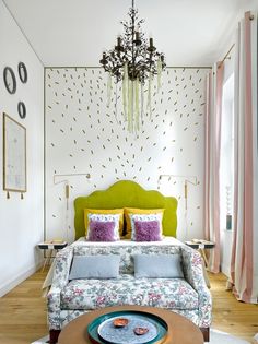 a bed room with a neatly made bed and a chandelier hanging from the ceiling