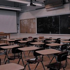 an empty classroom with wooden desks and chalkboard