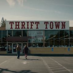 two people walking in front of a thrift town store with the words thrift town on it