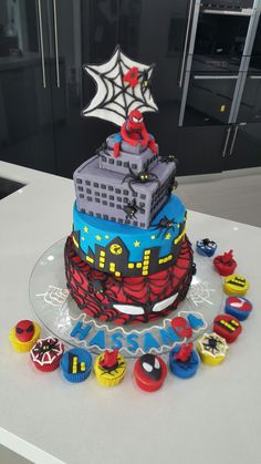 a birthday cake decorated with legos and spiderman cupcakes on a table