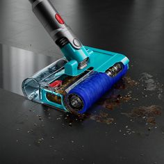 a close up of a person using a cordless vacuum cleaner on a black surface