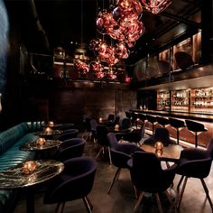 a dimly lit room with many chairs and tables in front of the bar, lights hanging from the ceiling