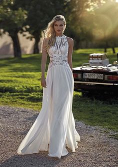 a woman in a white dress is standing on the road with her hands behind her back