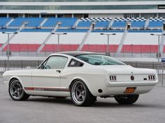 a white mustang parked in front of a stadium