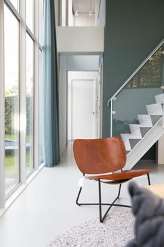 a chair sitting on top of a white rug next to a stair case in a living room