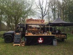 the food truck is selling hot dogs and other foods in the park with tents set up around it