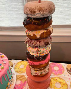 a stack of doughnuts sitting on top of a table next to a cake