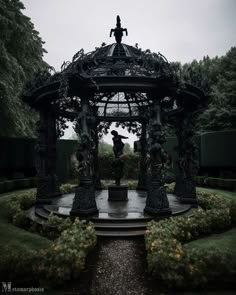 a gazebo in the middle of a park with trees and bushes on either side