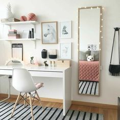 a white desk and chair in a small room with pictures on the wall behind it