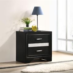 a black night stand with two drawers and a lamp on the floor next to it