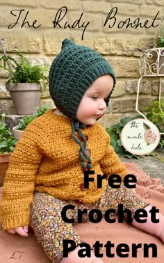 a small child sitting on the ground wearing a knitted hat