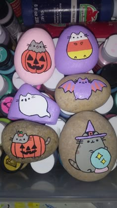 painted rocks with cartoon cats and pumpkins on them are displayed in a display case