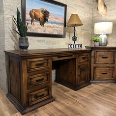 an office desk with two drawers and a painting on the wall above it, along with a lamp