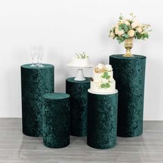 three green pedestals with cakes and flowers on them