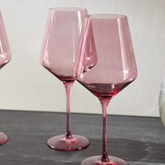 three pink wine glasses sitting on top of a table