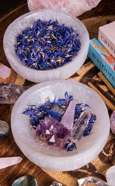 two white bowls filled with crystals on top of a wooden table next to other items