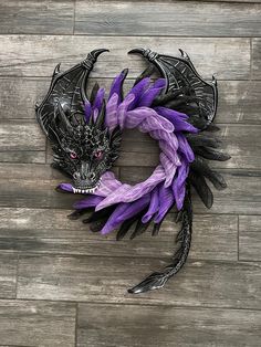 a purple and black dragon wreath on a wooden floor