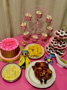 a pink table topped with lots of cakes and desserts next to a ferris wheel