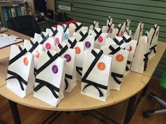 many bags with numbers and ribbons on them sitting on a table in front of a bookcase