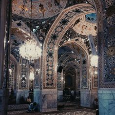 an ornate building with chandeliers hanging from it's ceiling and two people sitting on the floor