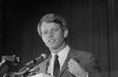 a man in a suit and tie standing at a podium with microphones behind him