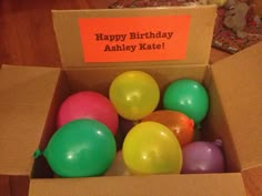 a box filled with balloons sitting on top of a wooden floor