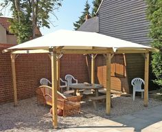 a wooden gazebo sitting next to a brick wall with chairs and tables under it