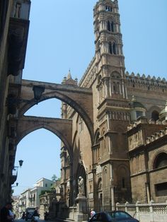 an old building with arches and a clock tower in the middle of it's street