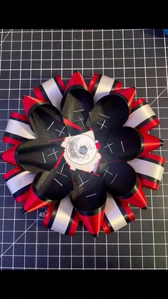 a red, white and black flower sitting on top of a cutting board next to scissors