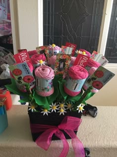 a vase filled with pink crochet yarn and lots of flowers on top of a table