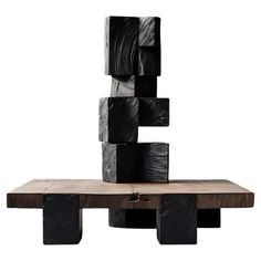 a wooden table topped with black cubes on top of it's sides and a piece of wood in the middle