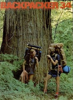 two people with backpacks are walking through the woods