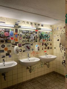 three urinals in a public restroom with graffiti on the walls and below them