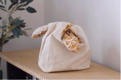 a white bag sitting on top of a wooden table next to a potted plant