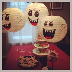 three paper lanterns with faces on them are sitting on a table next to cookies and pretzels