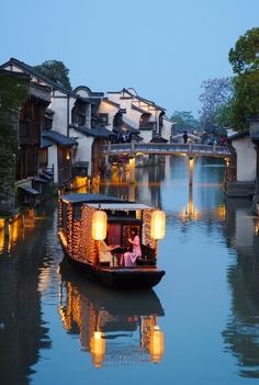 a small boat is traveling down the river at night with lights on it's sides