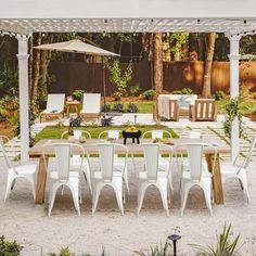 an outdoor dining area with white chairs and tables in the foreground is a black cat