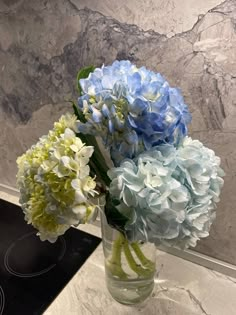 blue and white flowers are in a vase on the counter next to an electric stove