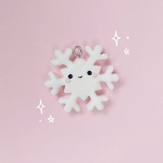 a white snowflake keychain on a pink background