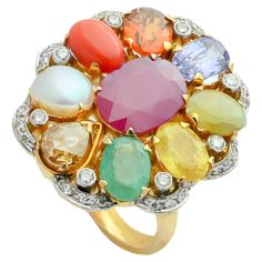 A simple 18K gold ring in the form of oval shape set with the nine planetary gems (navratna) and full cut diamonds. Starting with blue sapphire at the lower end, the nine gemstones include a coral, yellow sapphire, emerald, cat's eye, cultured pearl, hessonite garnet, blue sapphire and a natural ruby at centre. The concept of navratna is born at the core of Indian hindu culture, to attain the maximum prophylactic powers of the nine gems, the gems need to be set with open-back mounts so that light passed through the stones transmitting their energies to the body. The ring embodies nearly 11.50gms of fine gold and 14.21cts of natural stones accompanied with 0.60cts diamonds. Fine Jewelry Multicolor Oval Gemstones, Luxury Oval Multi-stone Diamond Ring, Luxury Multicolor Ruby Ring, Oval Multi-stone Gemstones, Multicolor Diamond Gemstones With Accents, Dazzling Oval Multi-stone Gemstones, Multicolor Oval Gemstones For Anniversary, Oval Multicolor Gemstones For Anniversary, Fine Jewelry Multicolor Cabochon Gemstones