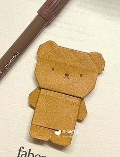 an origami bear with a pencil on it next to a paper cutout