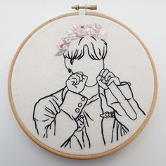 a hand embroidered portrait of a woman with flowers in her hair, on a white background