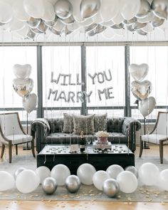 a living room filled with balloons and couches next to a wall that says, i will you marry me